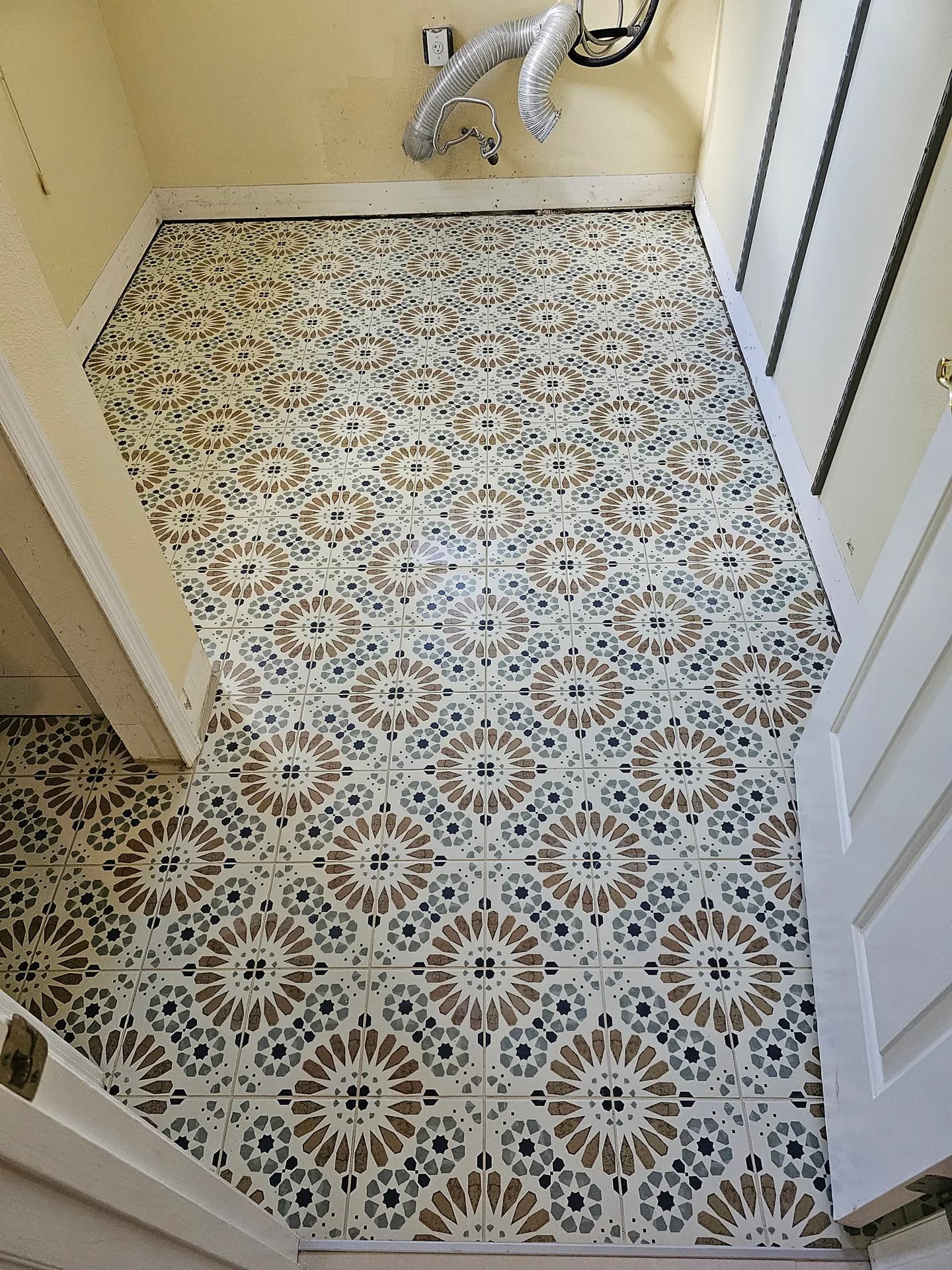 Decorative Moroccan-style patterned porcelain tile floor in cream, navy, and terracotta installed in a laundry room.