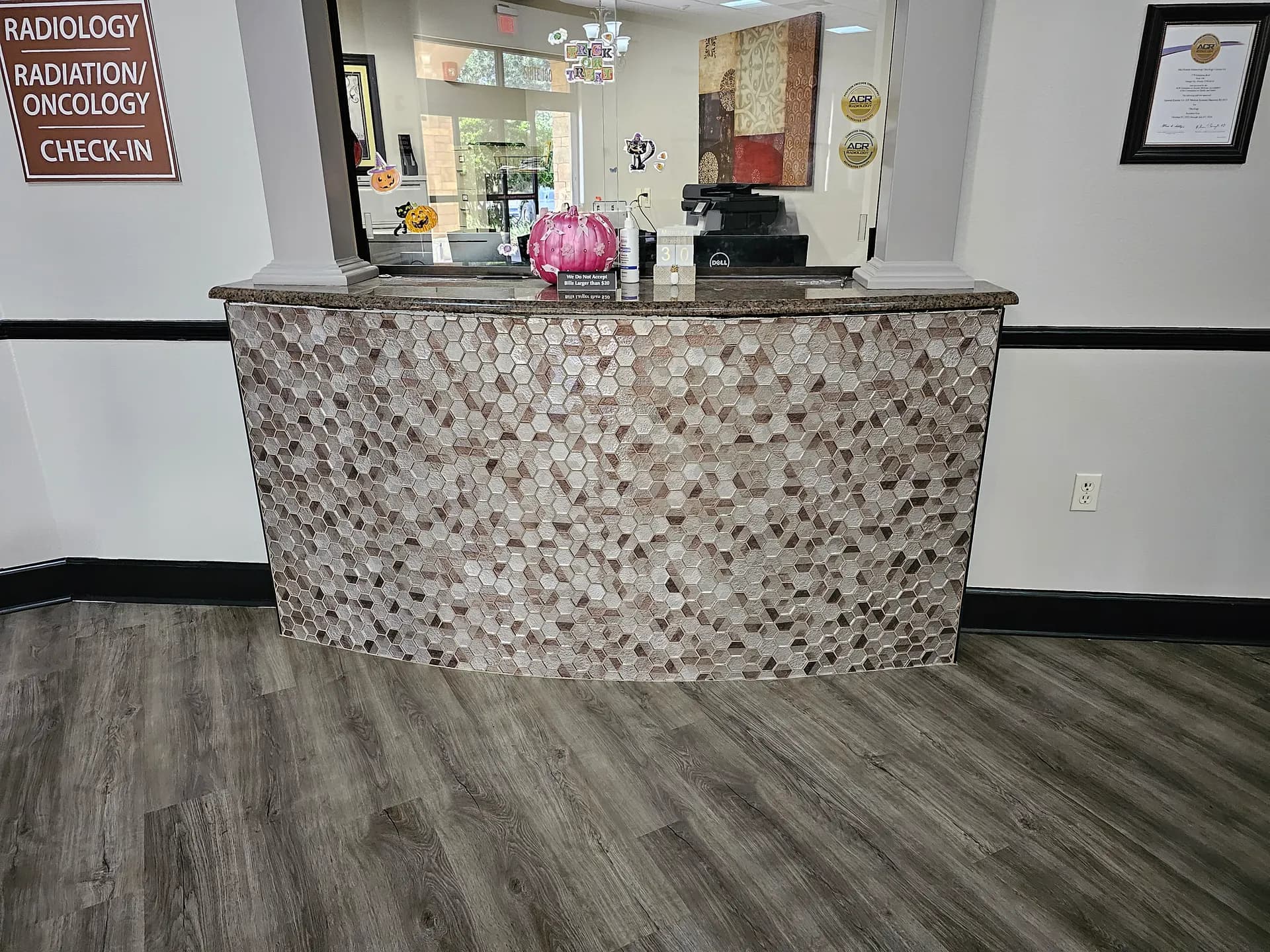 Completed hexagon glass mosaic on a curved check-in desk in a radiology office, paired with gray wood-look plank flooring.