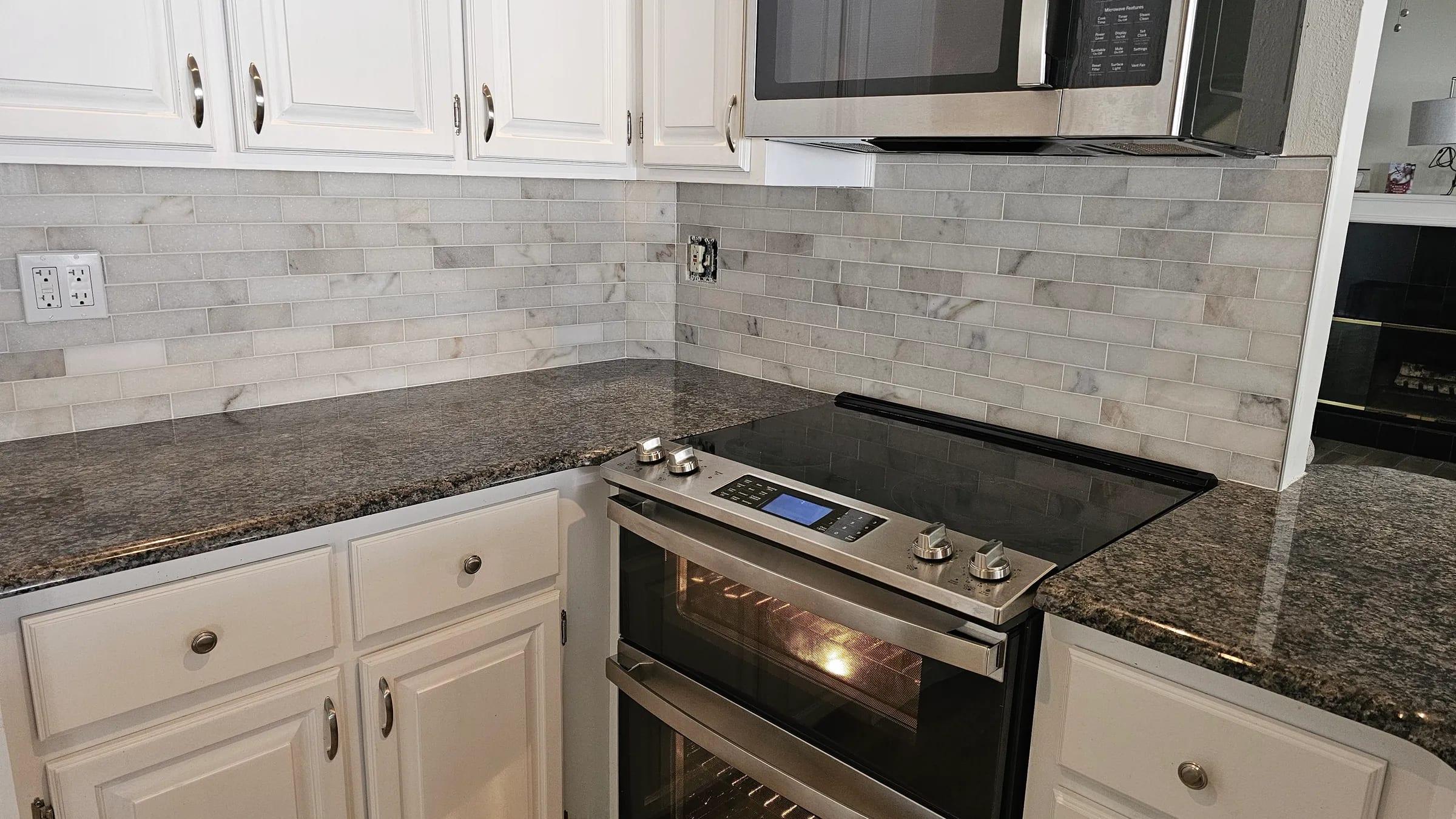 Marble subway tile backsplash in a classic offset pattern above dark granite counters